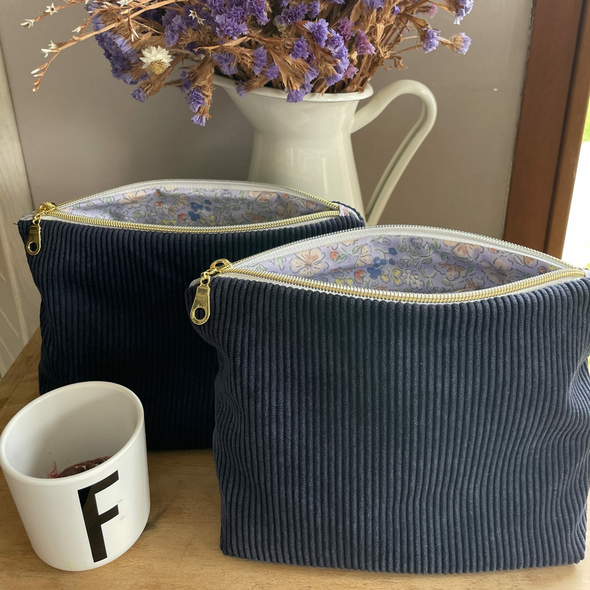 pochette zippée en velours côtelé bleu marine et motif intérieur fleurs